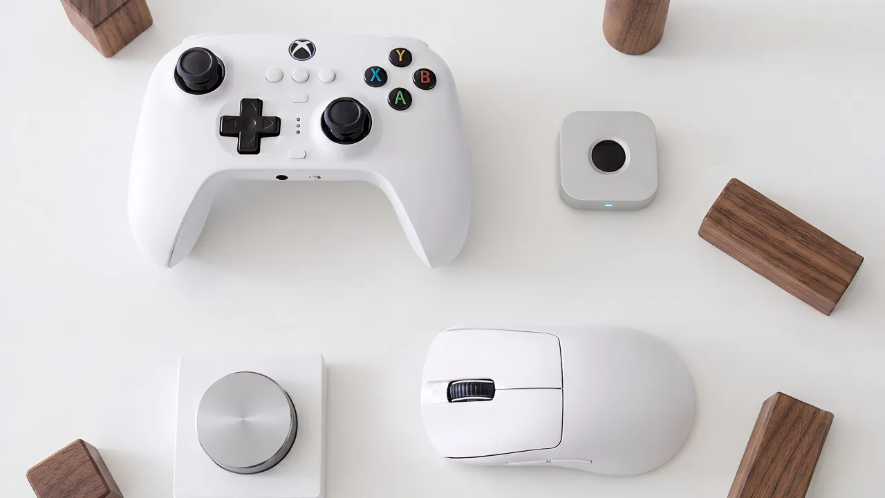 immurok fingerprint key on a white desk next to a wireless game controller, a mouse and a volume knob